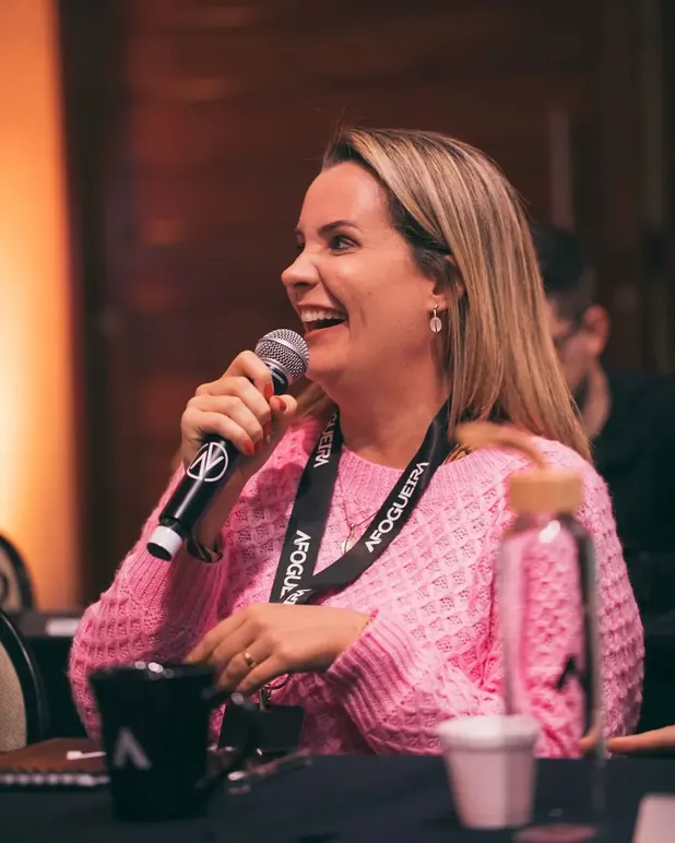 Cris Herzog falando ao microfone em evento ao vivo