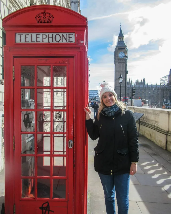 Cris Herzog em Londres, ao lado de uma cabine telefônica